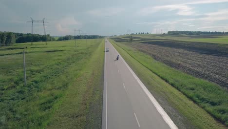 upper-view-people-ride-black-motorcycle-along-gray-road