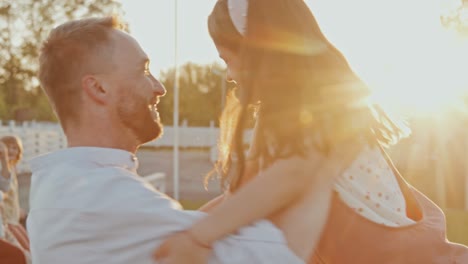 dad circling daughter in arms in sunlight