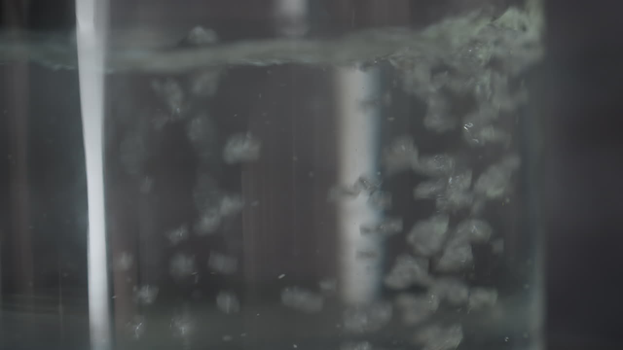 Tall Glass With Rising Bubbles And Delicate Effervescence, Soft Muted Light, Rhythmic Ascent Of Microbubbles, Crystal Clarity, Minimal Ambient Background, Close Macro On Sparkling Surface And Tiny