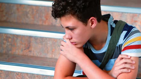 triste escolar sentado solo en la escalera