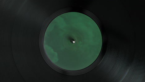 spinning vinyl record: top view of the turntable spindle and a green label, close up