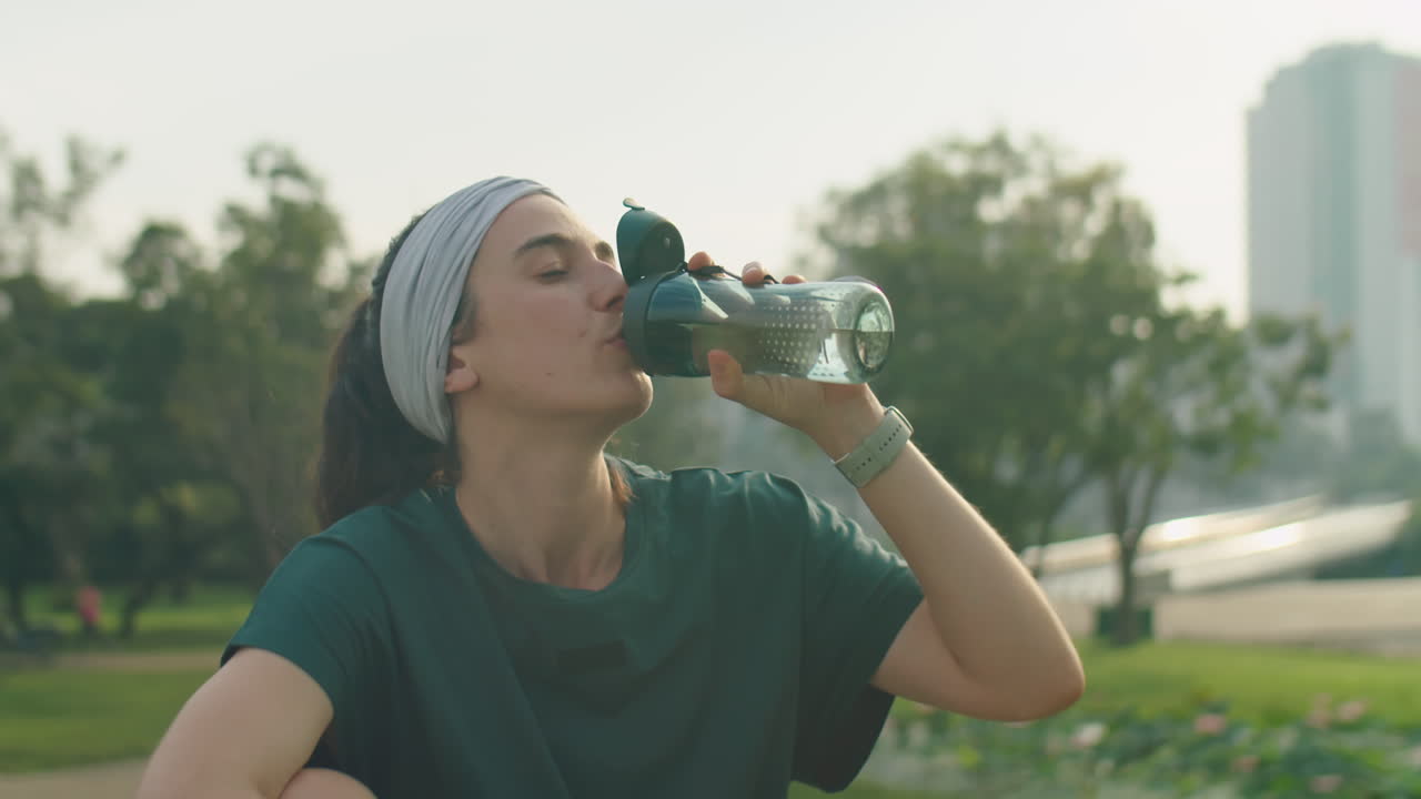 Woman Drinking Water after Workout in Park