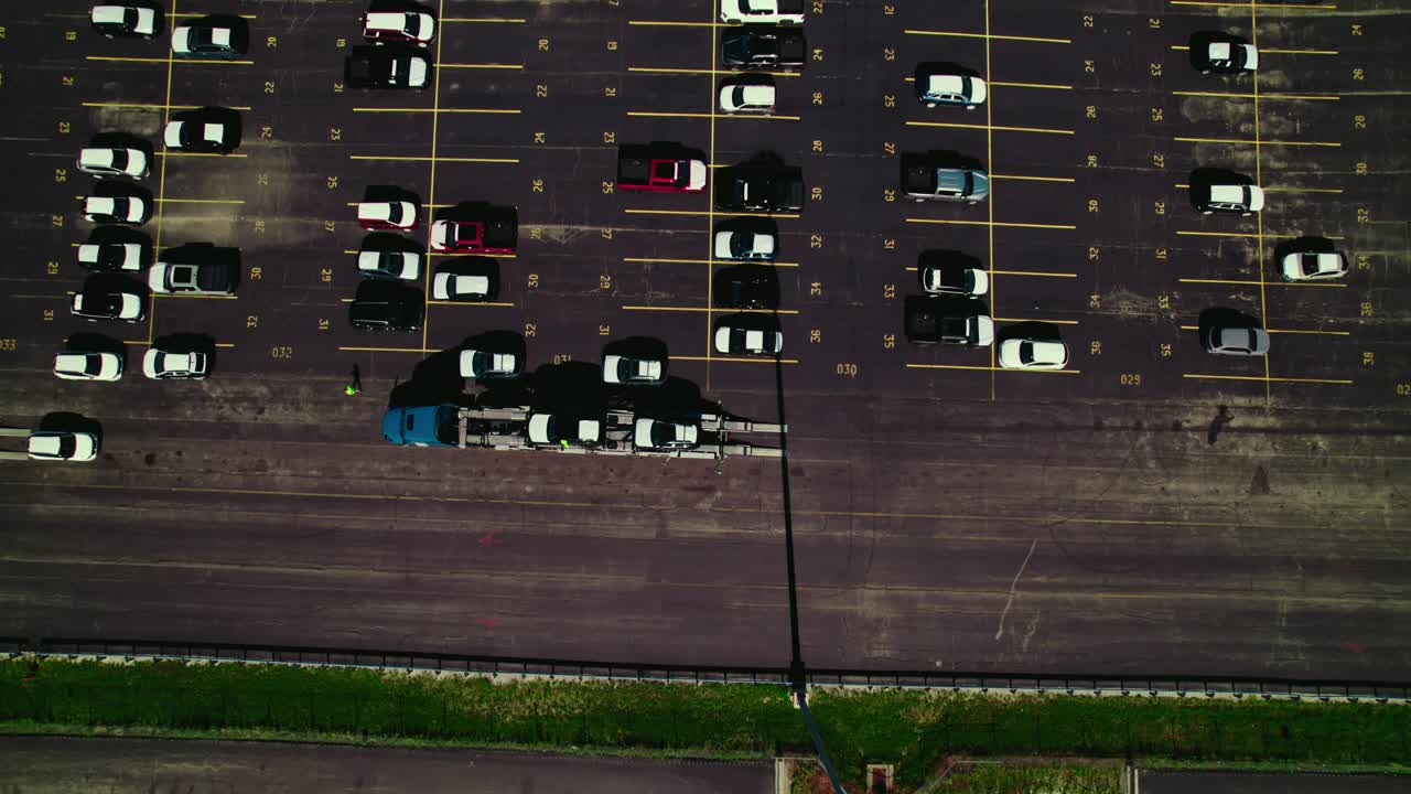 Aerial view over a car carrier trailer, car hauler truck, loading with new cars from a parking lot