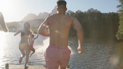 Grupo-De-Amigos-Corriendo-Saltando-Del-Embarcadero-En-El-Lago-Al-Atardecer-Divirtiéndose-Chapoteando-En-El-Agua-Disfrutando-De-La-Libertad-Compartiendo-Aventuras-De-Verano