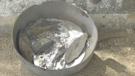 molten lead in a metal container with a propane torch heating, close up