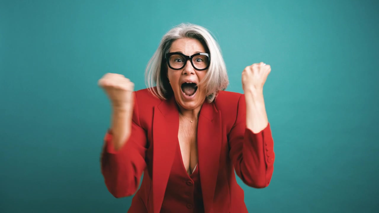 Donna matura entusiasta che celebra il successo su uno sfondo verde acqua