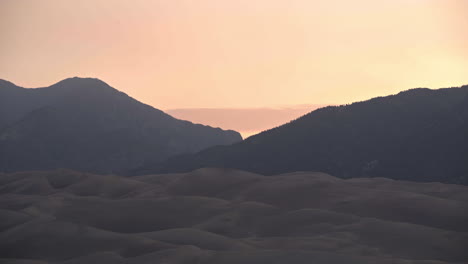 sol saliendo detrás de las montañas en el parque nacional de las grandes dunas de arena colorado