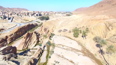 drone-shot-of-a-waterfall-between-desert-mountains-in-bousaada