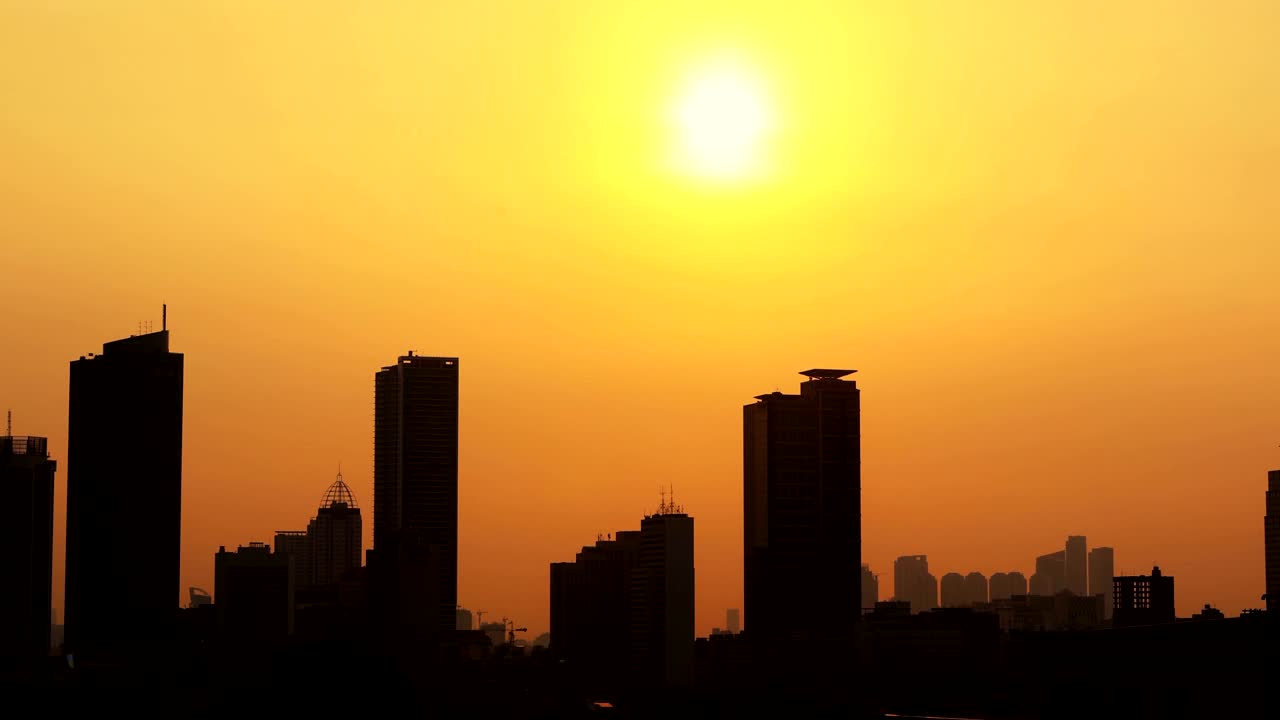 Time-lapse del atardecer con silueta de edificios de oficinas modernos.
