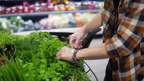 young man with a protective black mask walking in a supermarket and take greens from the shelf. corona virus idea