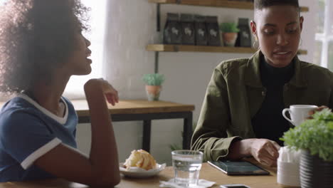 young black women friends in cafe talking drinking coffee enjoying conversation socializing together sharing friendship connection in restaurant shop