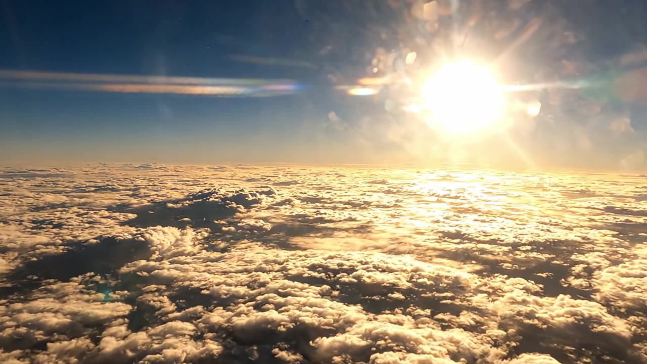 A breathtaking view of the sun rising brightly above a vast sea of clouds, showcasing the beauty of nature from an aerial perspective.