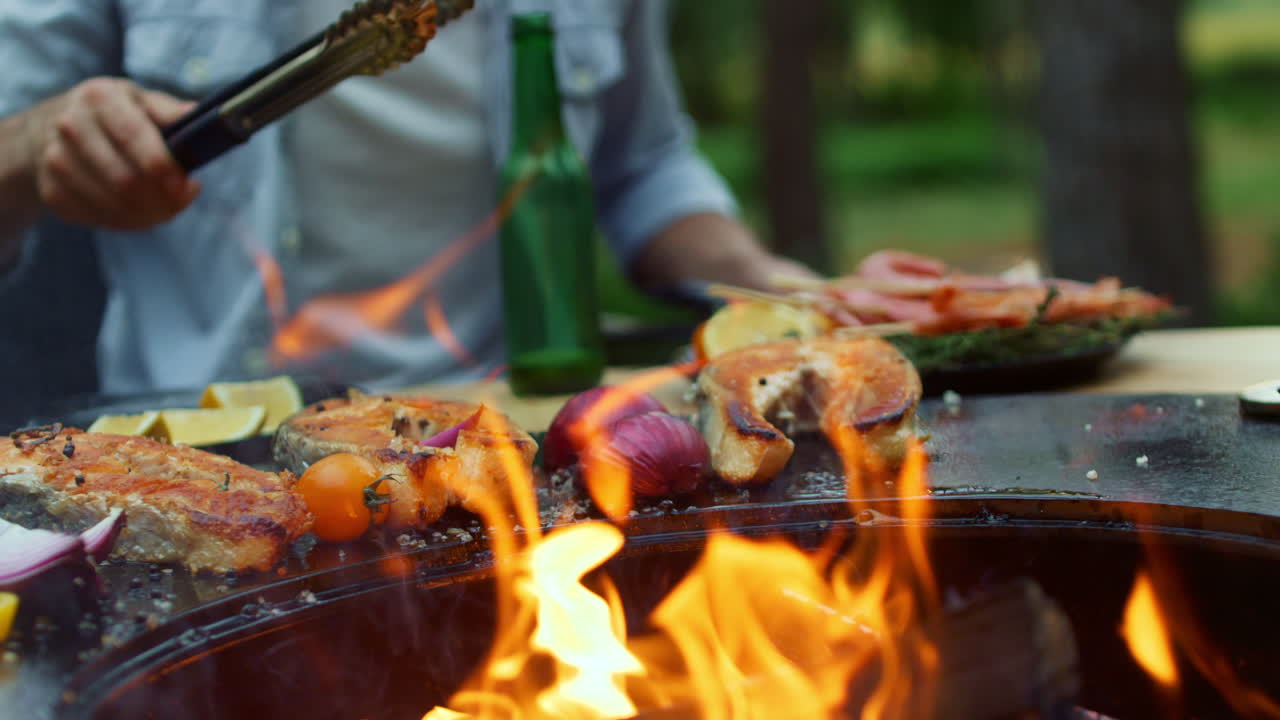 Uomo irriconoscibile che cucina pesce sulla griglia all'aperto. Chef che finisce il processo di cottura.