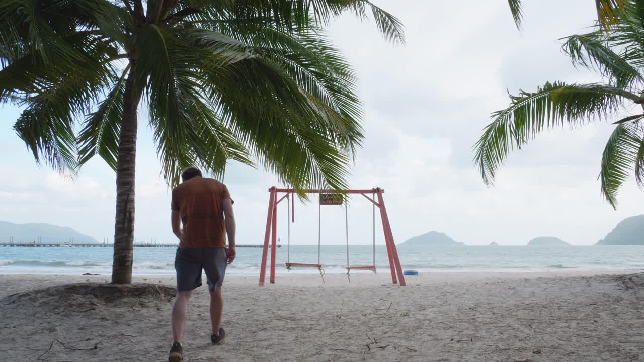 hombre blanco sentado en un columpio frente a la playa de bai tam an hai en la isla de con dao, vietnam