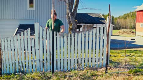 portrait of a man working on the yard with an old wooden fence. static shot