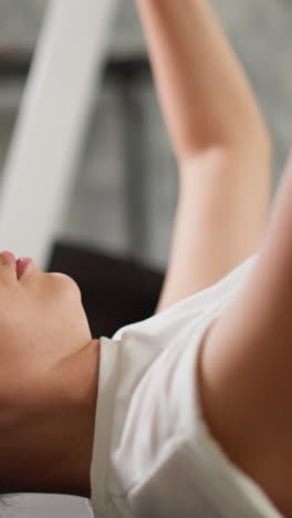 mujer levanta los brazos con pesas en las manos. entusiasta deportiva comprometida se dedica a esculpir los músculos del brazo usando pesas en el espacio de fitness en el hogar