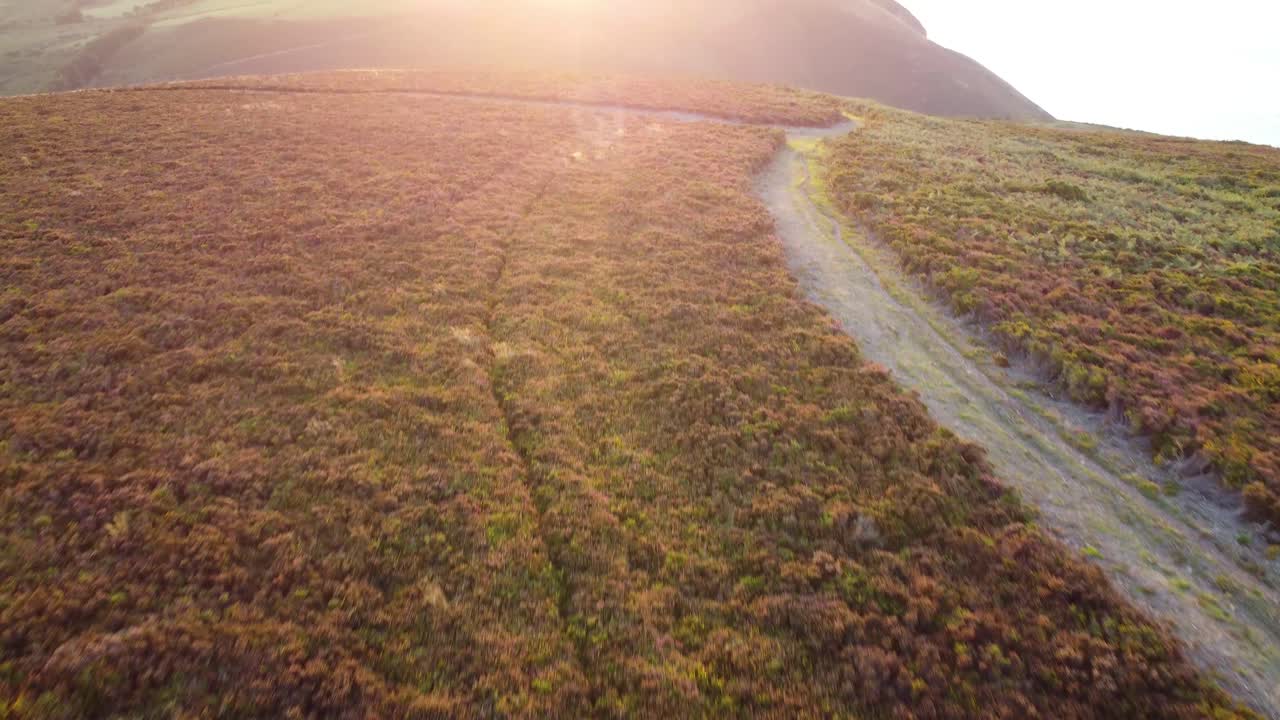 imágenes aéreas de drones que revelan la puesta de sol sobre el camino de la costa y los campos ondulados en north devon, reino unido 4k