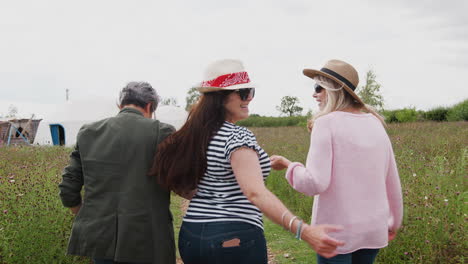 Rear-View-Of-Mature-Female-Friends-Walking-Along-Path-Through-Yurt-Campsite