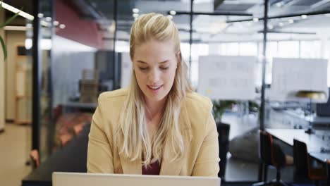 Happy-plus-size-caucasian-casual-businesswoman-using-laptop-at-desk