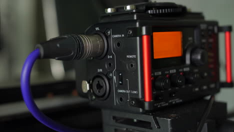 un hombre conectando un cable de micrófono xlr a una grabadora de campo de audio en un estudio de producción de vídeo
