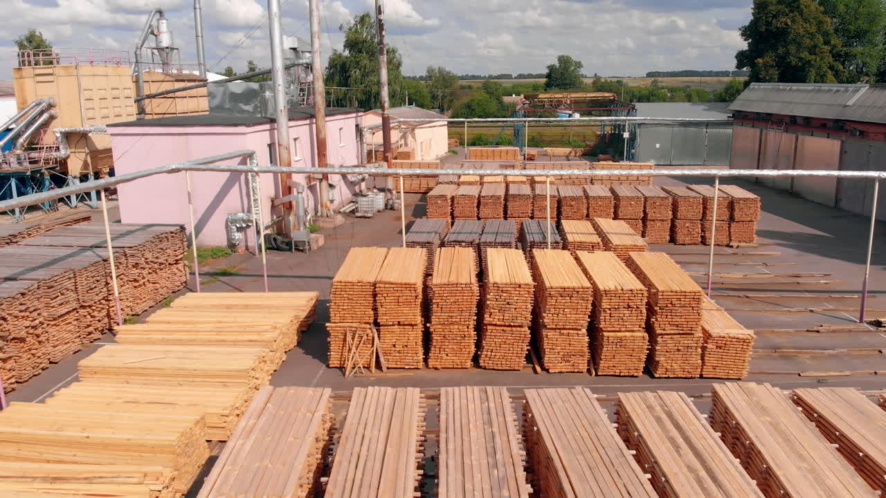 Big stacks of lumber materials stored outdoors. Industrial plant zone for doors making on sunny day.