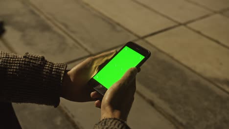 arab man using chroma key smartphone while walking through night city street.