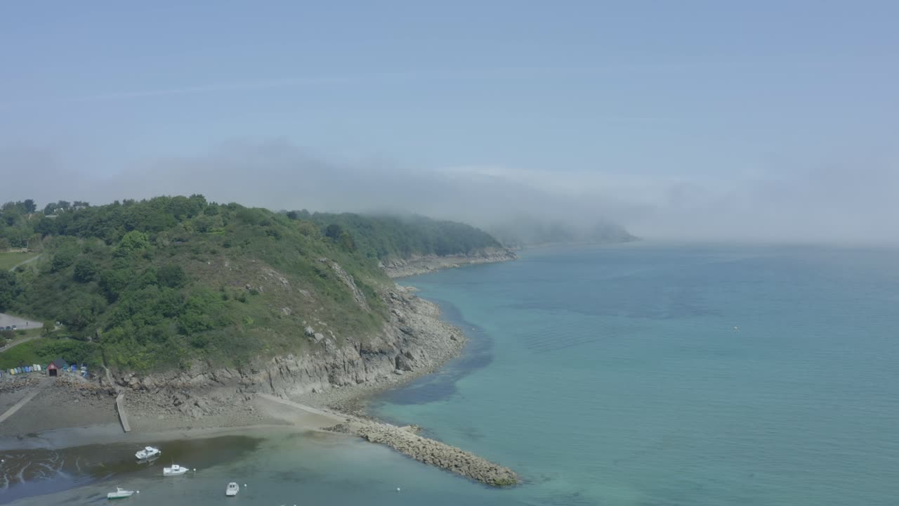 живописный вид на прозрачное голубое море на полуострове бретань, франция, с пышным скалистым прибрежным утесом, увенчанным облаками