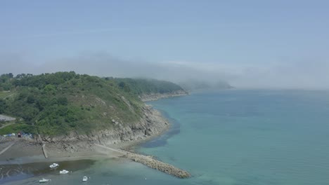 Vista-Panorámica-Del-Mar-Azul-Claro-En-La-Península-De-Bretaña,-Francia,-Con-Un-Exuberante-Acantilado-Costero-Rocoso-Cubierto-De-Nubes