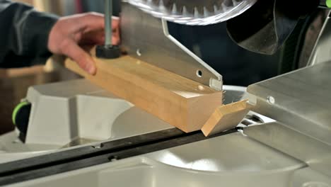 close-up of a man's hand working on a machine with a circular saw