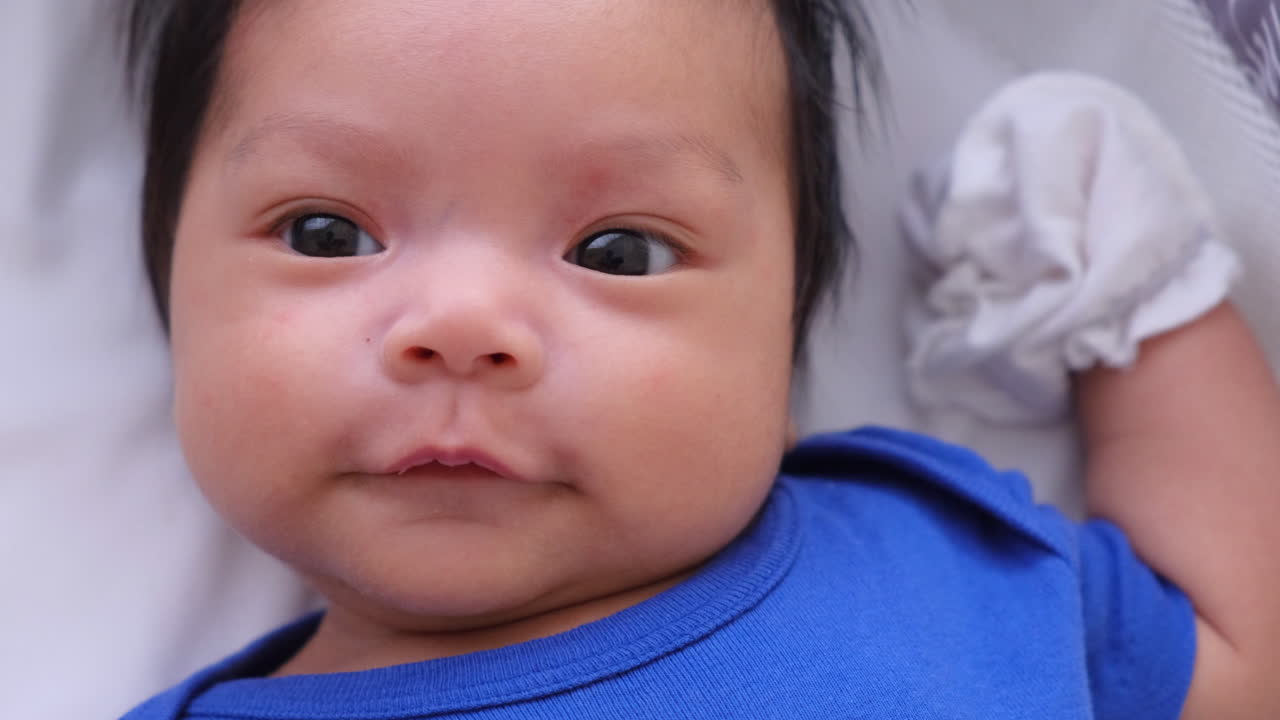 lindo bebé acostado despierto y moviéndose en la cama