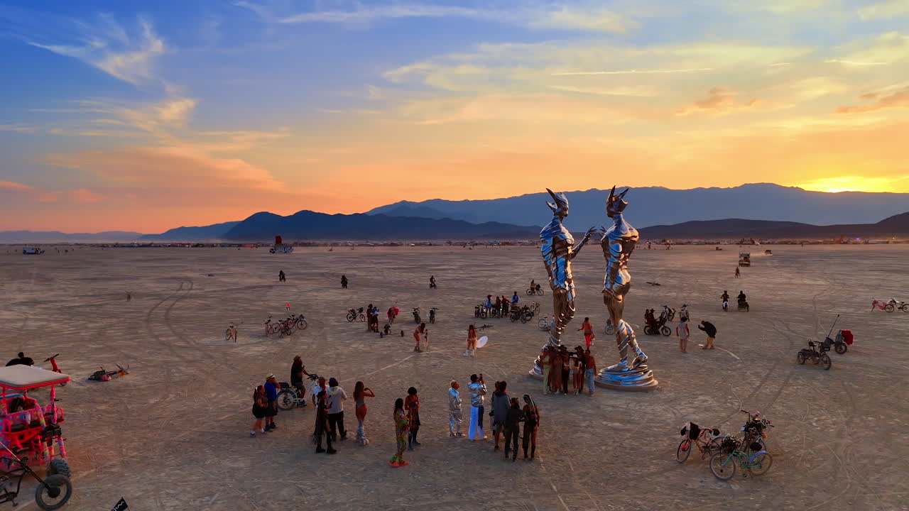 Nevada, USA, 22 August 2025: Crowd at Burning Man desert art installation. People gather around tall metallic art sculptures in the desert during Burning Man festival at sunset