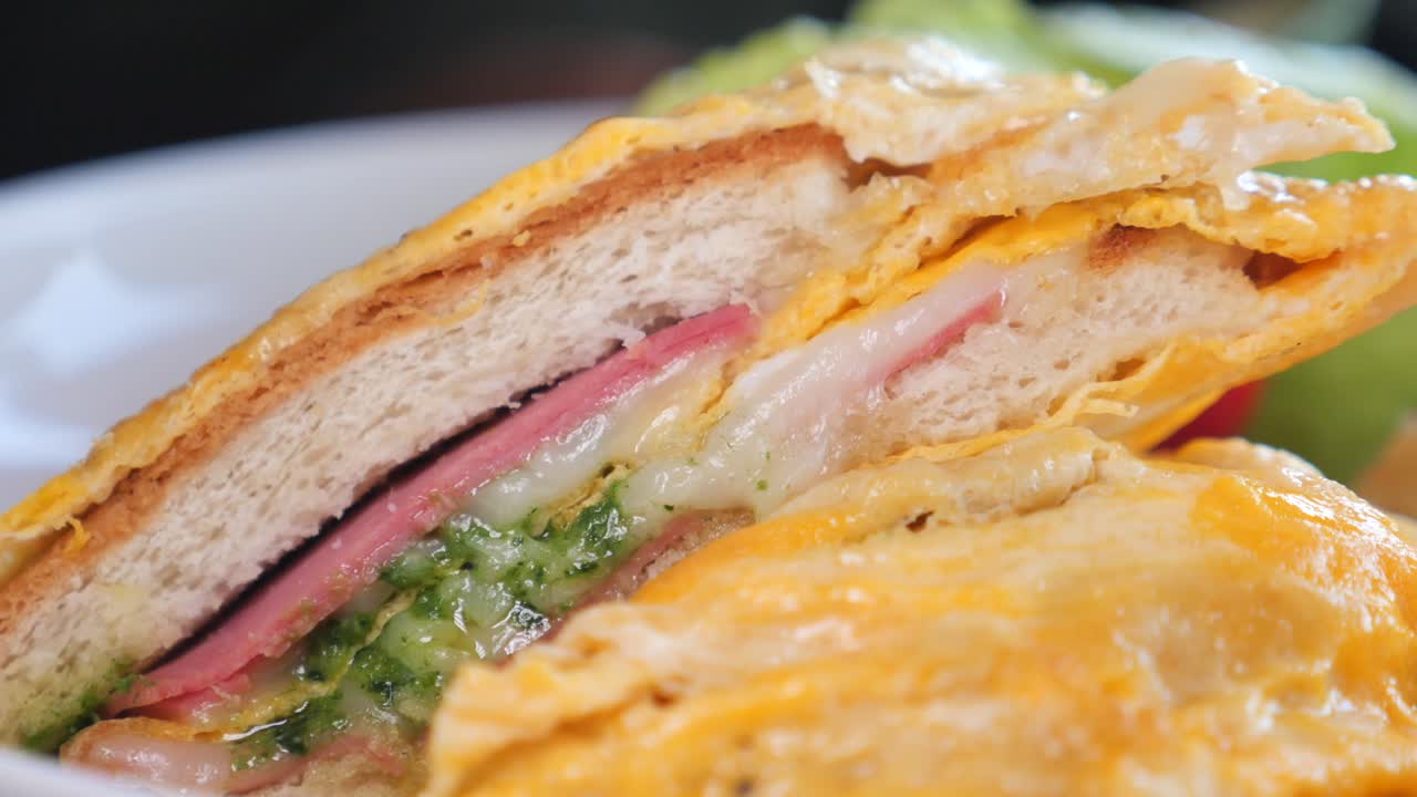 Close-up of a ham and cheese sandwich with pesto