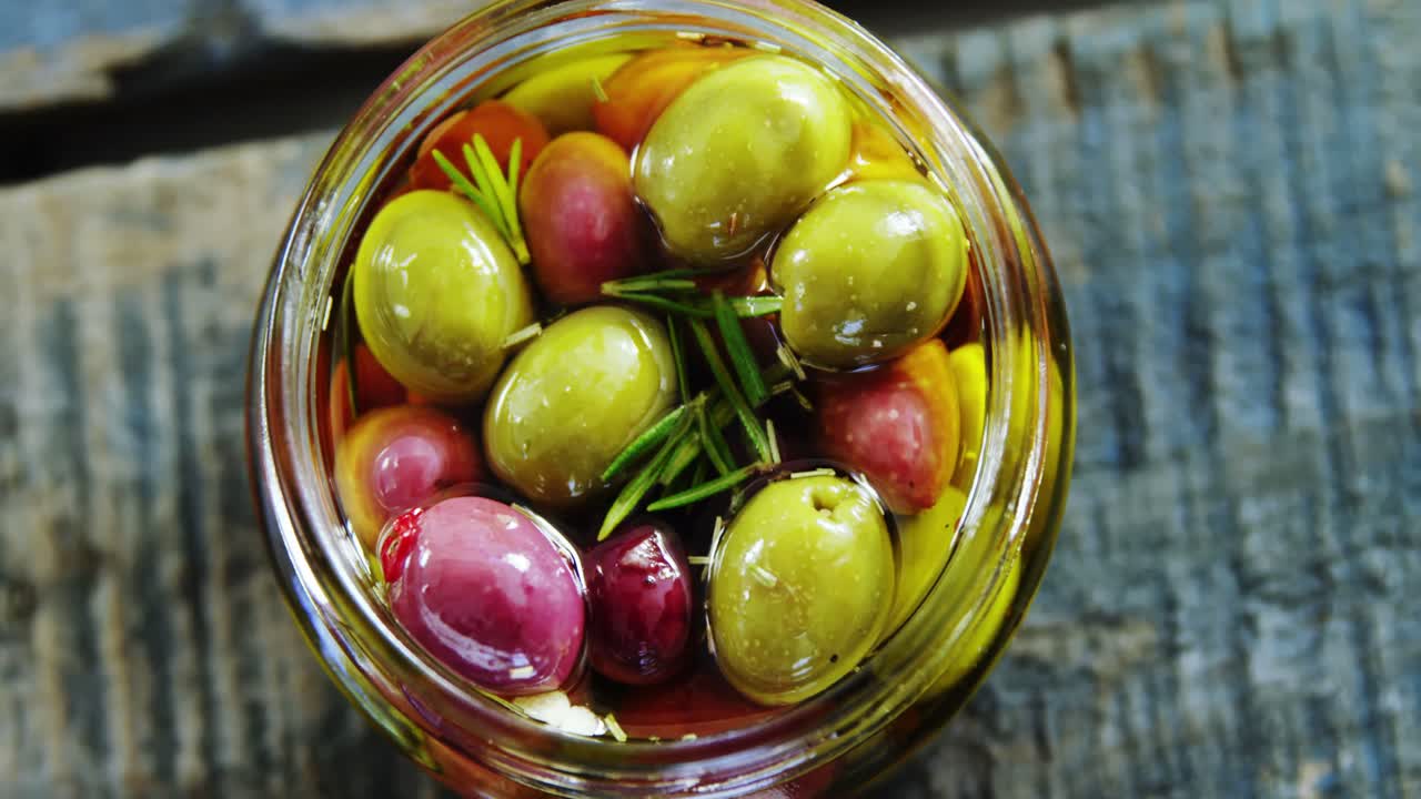 aceitunas y hierbas en vinagre en un frasco