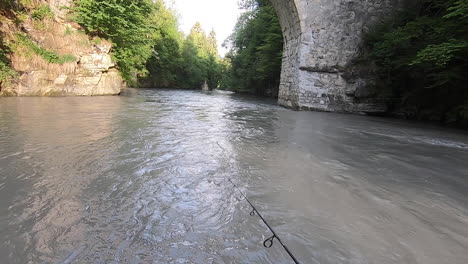 Un-Pescador-Se-Tambalea-En-Un-Gran-Río-Con-Una-Fuerte-Corriente-En-Los-Alpes-Suizos,-Pescando-Truchas