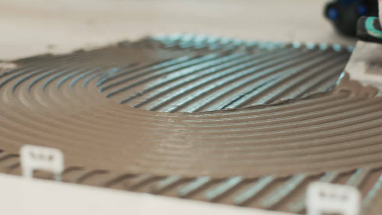 Spreading tiles adhesive on a floor with notched trowel