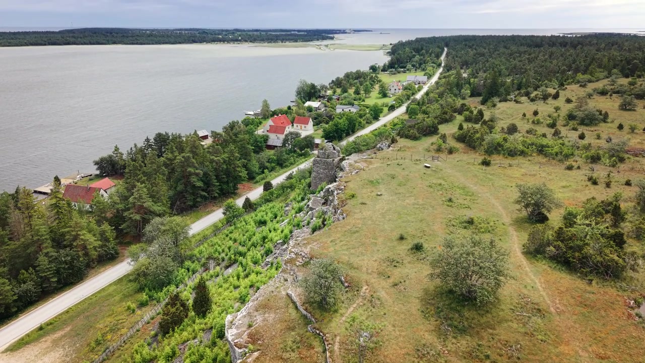 Drone-näkymä kallionrinteen kiviraunioista mutkittelevan tien ja pienen rannikkokylän vieressä ruotsalaisella saarella, jota ympäröi karu kalkkikivimaisema