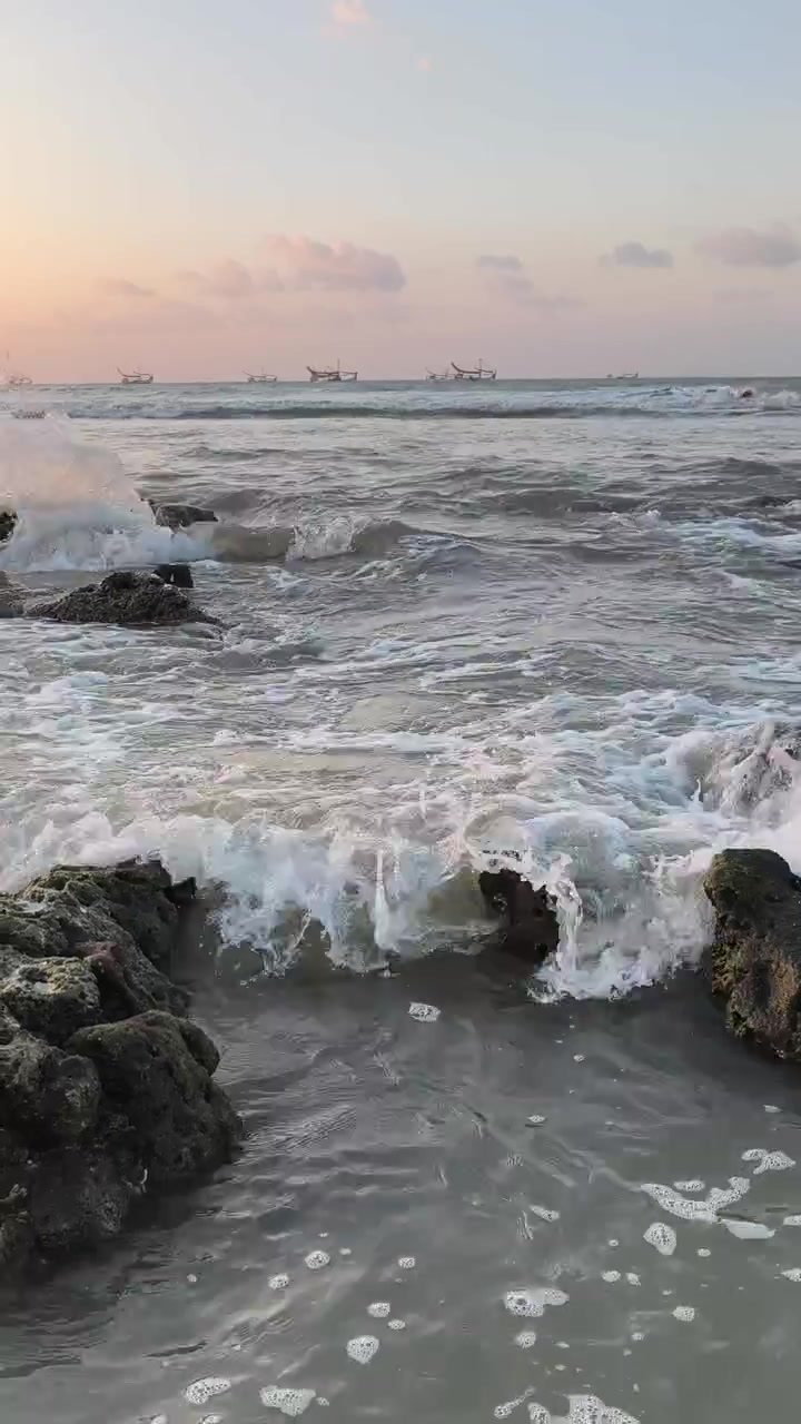 Le onde dell'oceano si schiantano contro la costa rocciosa al tramonto