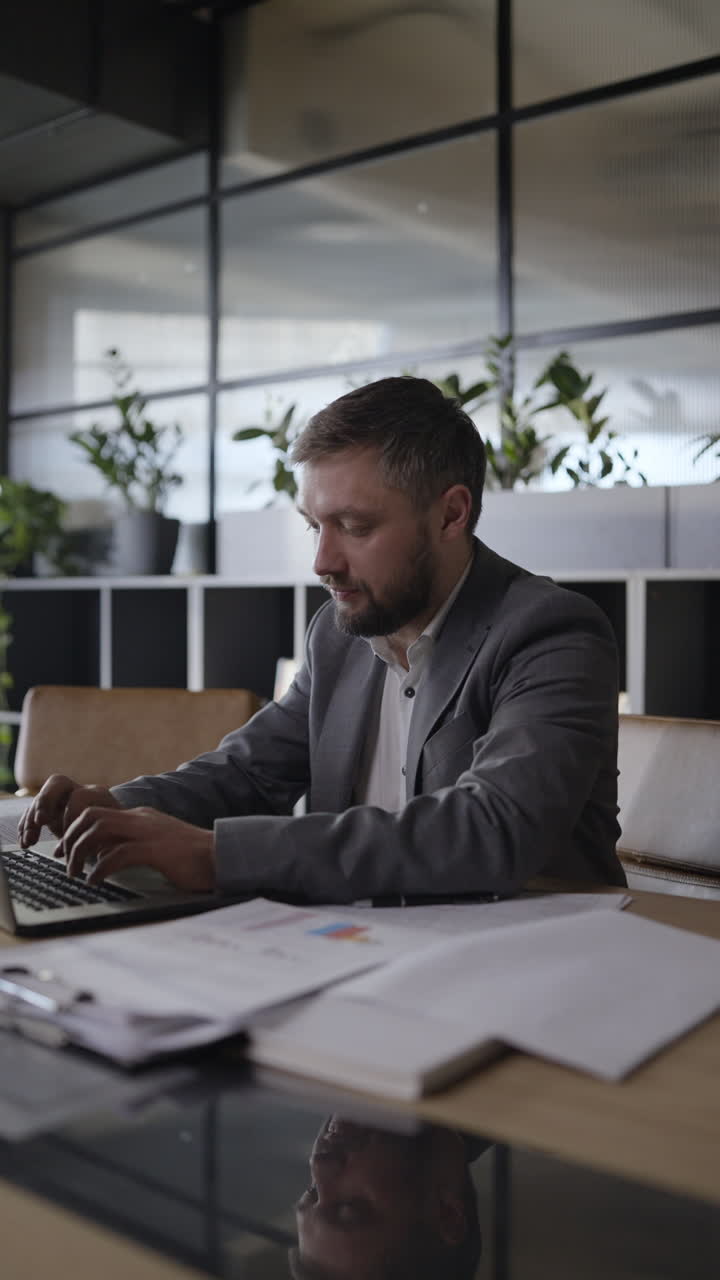 Businessman working on laptop and reports in modern office