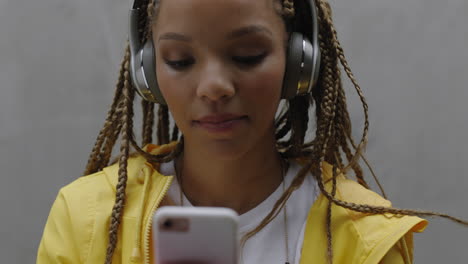 beautiful young mixed race woman using smartphone browsingf social media wearing headphones listening to music enjoying mobile communication close up