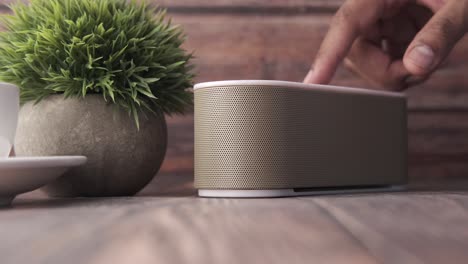 hand adjusting portable speaker on a wooden table