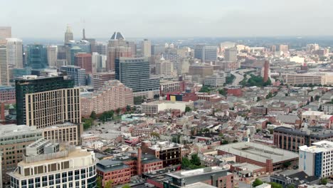 cinematic high aerial of downtown baltimore skyline and cityscape, financial center skyscrapers, highway, residential homes in fells point neighborhood