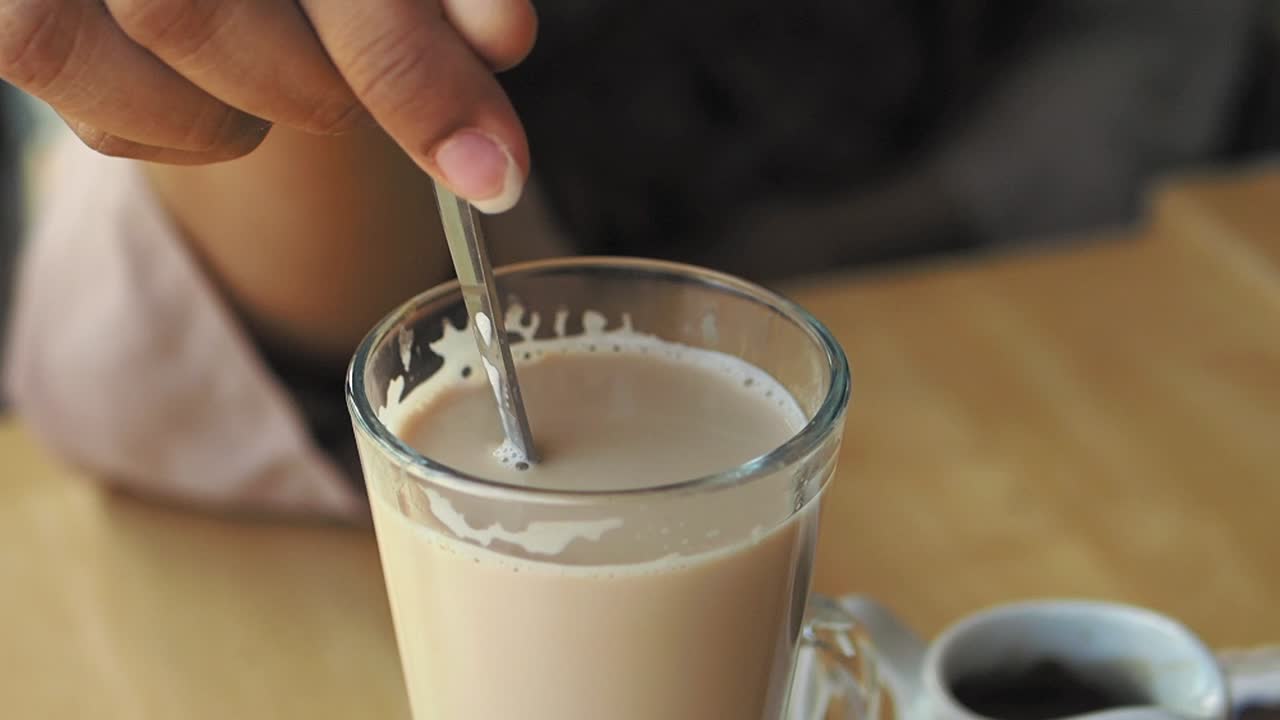 Donna che mescola il caffè in una tazza di vetro