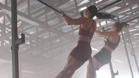 doing pull-ups, two women exercising in gym, focusing on fitness training