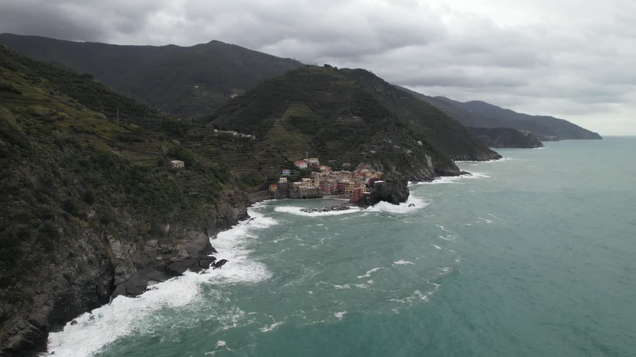 zoom en aerial toma de drone de cinque terre pueblo italiano ciudad junto a la playa olas que se estrellan