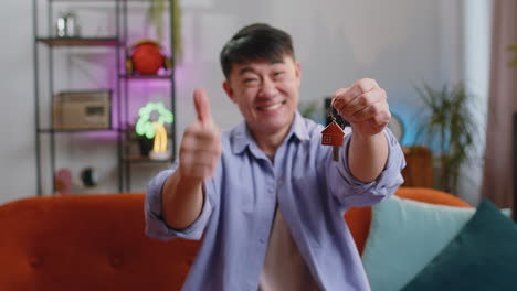 asian man real estate agent showing the keys of new home house apartment, buying or renting property