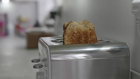 two slices of toast pop out of a toaster and a man takes them