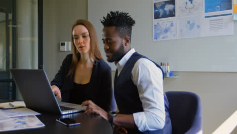 Side-view-of-young-cool-mixed-race-business-team-planning-and-sitting-at-table-of-modern-office-4k