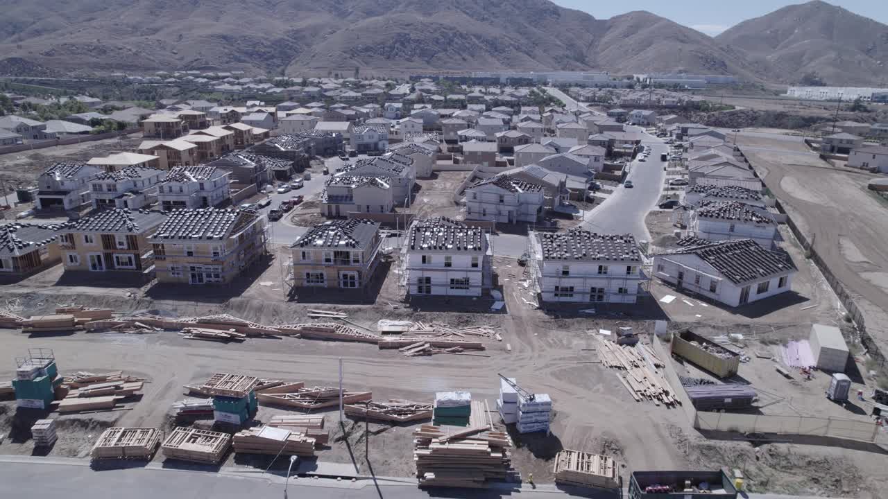 una cautivadora toma de drone se aleja de un sitio de construcción de casas, con la cámara inclinada para revelar la inmensidad de la construcción en curso, mostrando la escala y el dinamismo de todo el proyecto