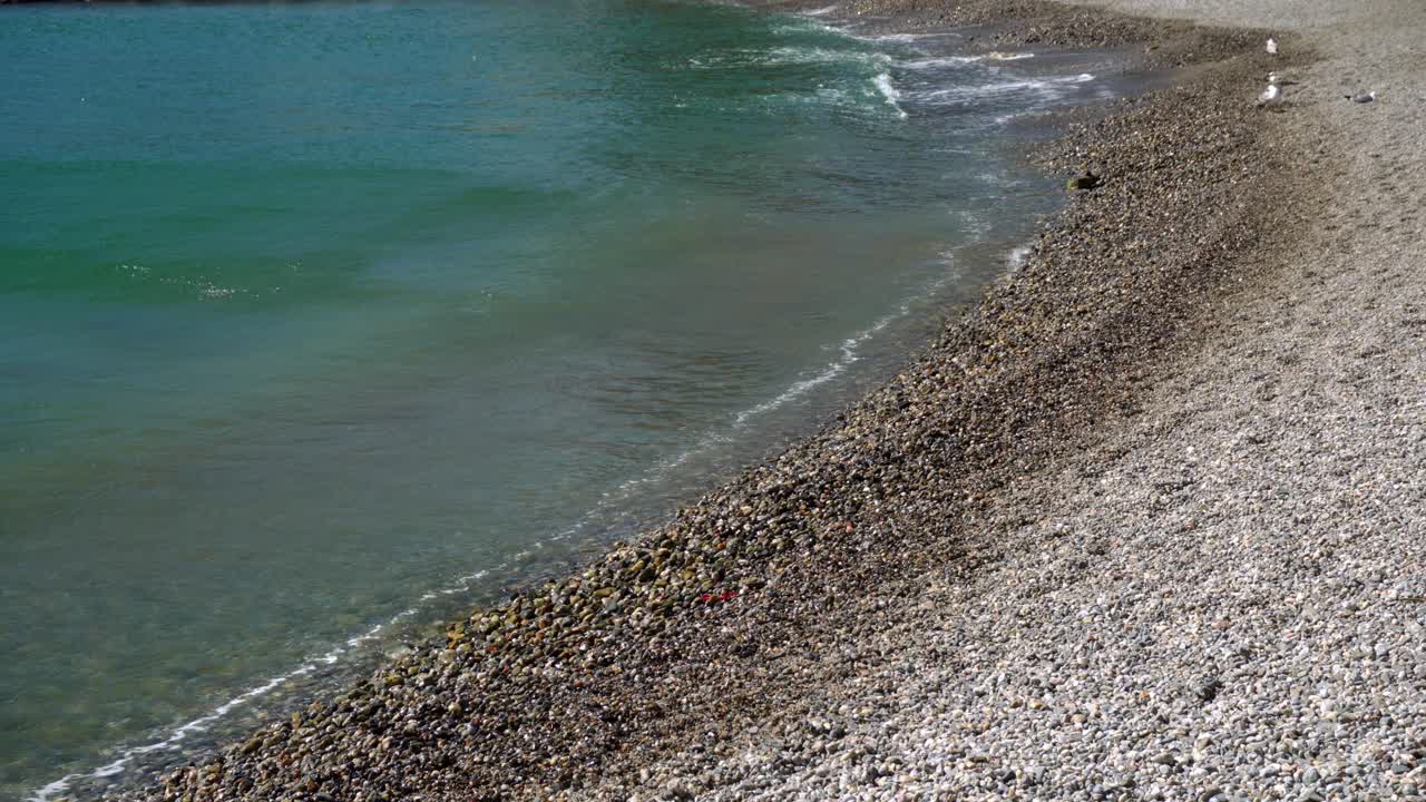 Primer plano de suaves olas rompiendo en una tranquila playa de guijarros en Collioure en un día ventoso