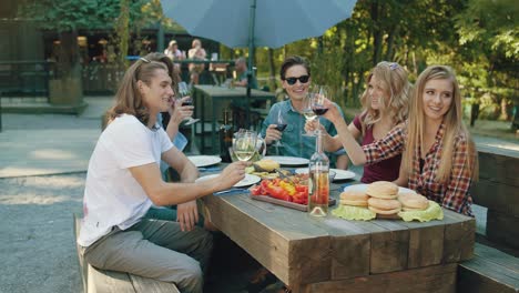 friends toasting with drinks at dinner party outdoors.